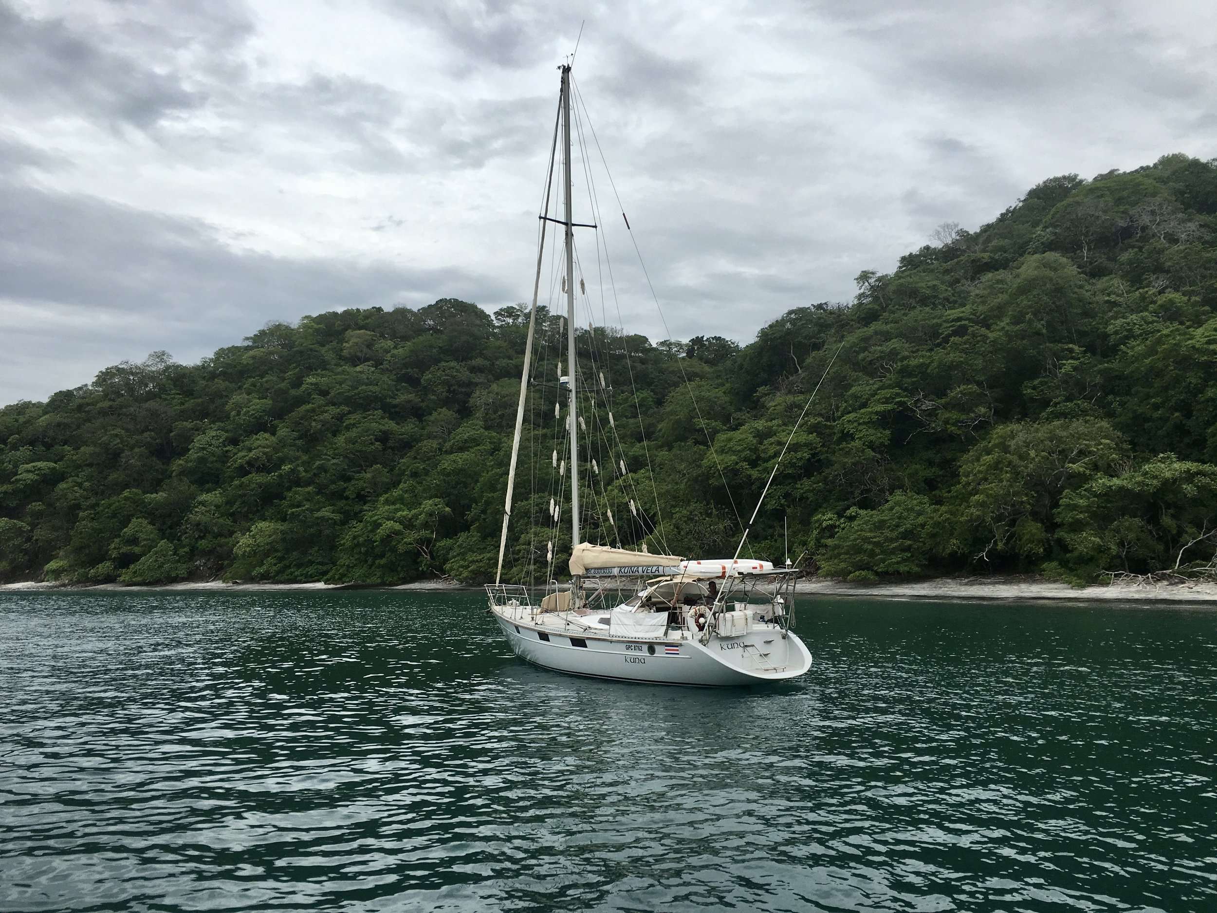 Sailboat with sials down off the lush jungle coast of Playa Hermosa Guanacaste Costa Rica